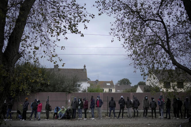 Migrants wait for a food distribution in Calais on October 14, 2021.