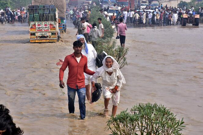 Des habitants de Rampur traversent une autoroute innondée après la crue de la rivière Kosi, dans l’Etat indien de l’Uttar Pradesh, le 20 octobre 2021.