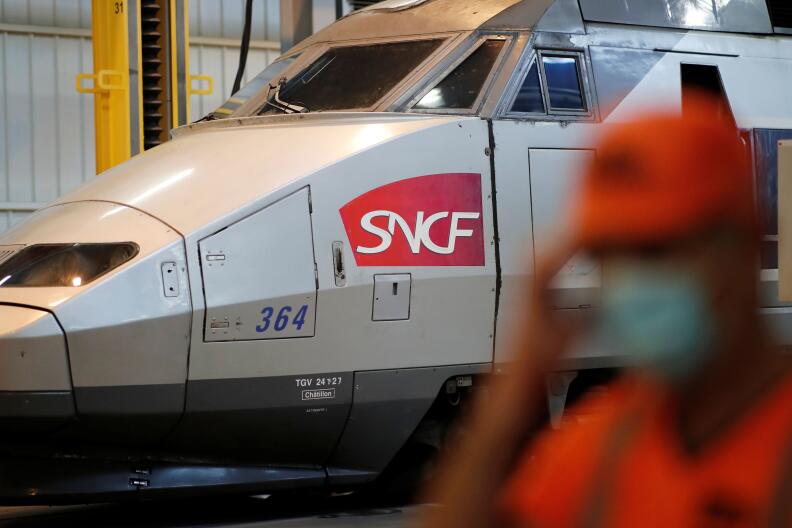 An employee walks towards a passenger train used on the TGV Atlantique line of the SNCF network sitting at the Technicentre workshop in Rennes, France, October 20, 2021. REUTERS/Benoit Tessier