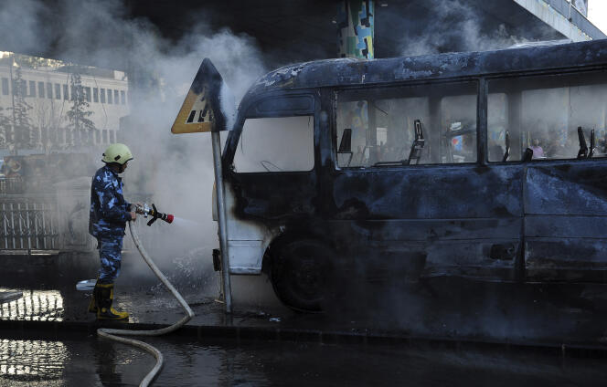 Un pompier syrien éteint le feu qui a pris dans un bus militaire après un attentat à la bombe, à Damas, le 20 octobre 2021.