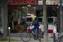 A Parisian woman rides her bicycle in front of a filling station, in Paris, France, Thursday, Oct. 21, 2021. France's government is planning measures this week to help drivers cope with rising gasoline prices, amid growing public discontent over a global energy crunch that is hitting just as many households are struggling to recover from the pandemic economic crisis. (AP Photo/Francois Mori)