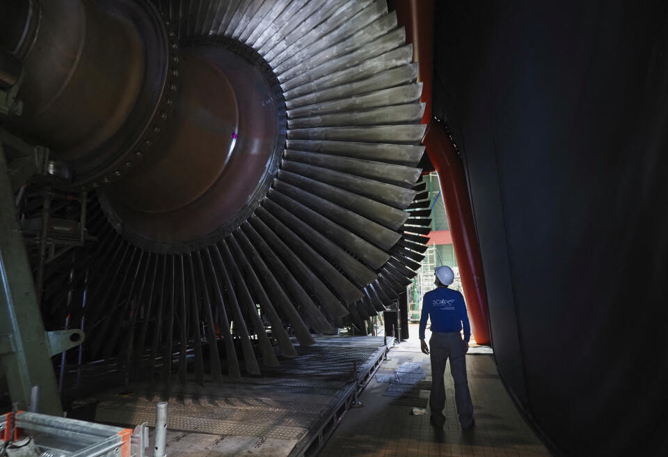 A worker stands by the rotor turbine which is being repaire on-site, in the engine room of the nuclear power plant of Chinon in Avoine, central France on July 8, 2020 during a decennial control visit. (Photo by GUILLAUME SOUVANT / AFP)