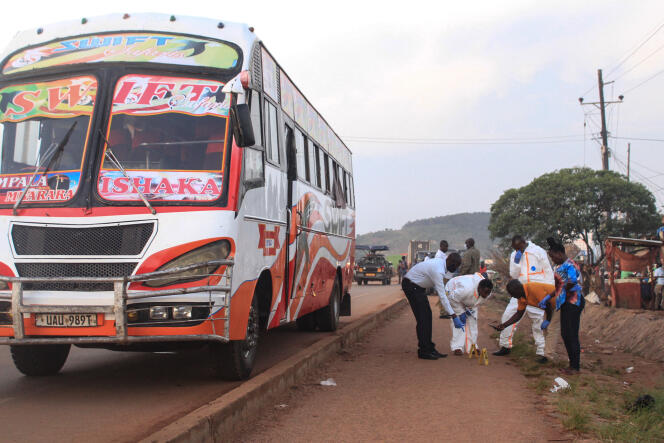 Des policiers ougandais enquêtent sur la scène de crime de l’explosion dans un bus, où au moins une personne est morte et plusieurs ont été blessées, près de Kampala, le 25 octobre 2021.
