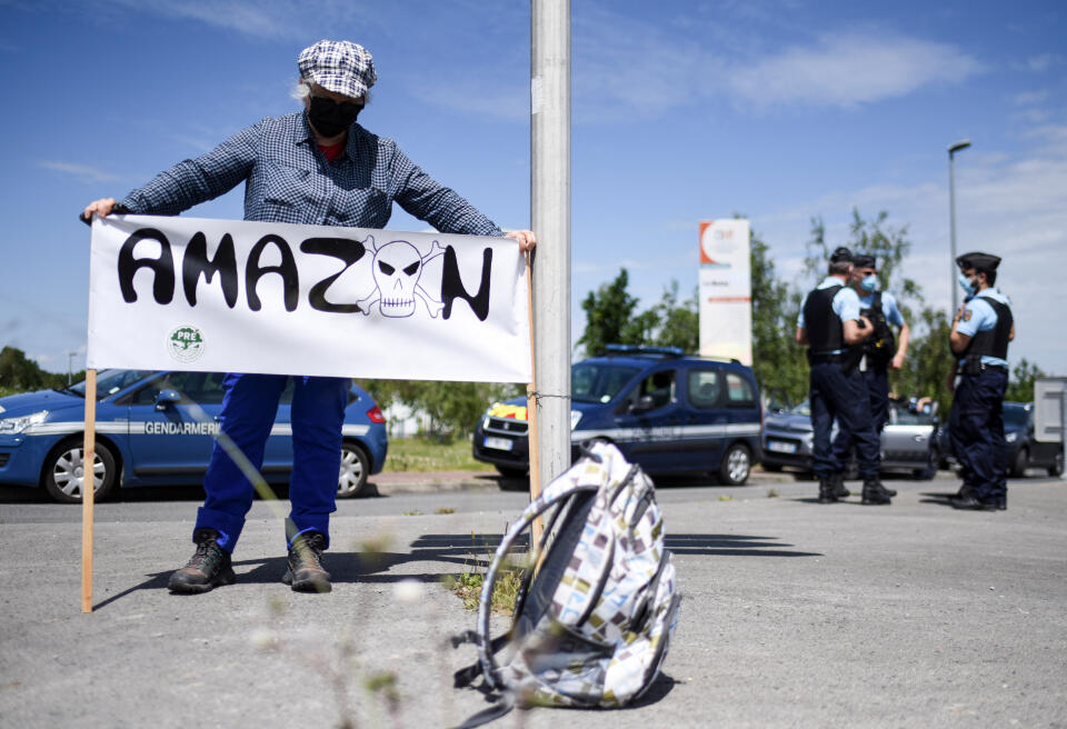 A woman shows a banner reading "Amazon" during a rally against the project to build an Amazon platform in Monbert, near Nantes, western France, on May 29, 2021. - Opposed to the implantation of warehouses of the US giant of the online trade Amazon, more than 600 people gatheredc near the protected site of the Pont du Gard, and nearly 500 in Montbert near Nantes. (Photo by Sebastien SALOM-GOMIS / AFP)