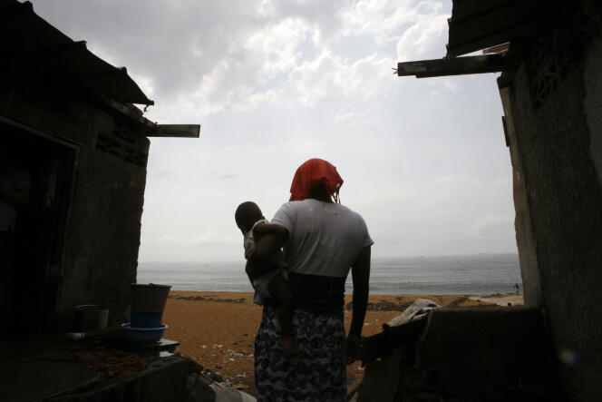 A woman and her baby walk along an eroded beach in Port-Bouët, Côte d'Ivoire, in December 2009.