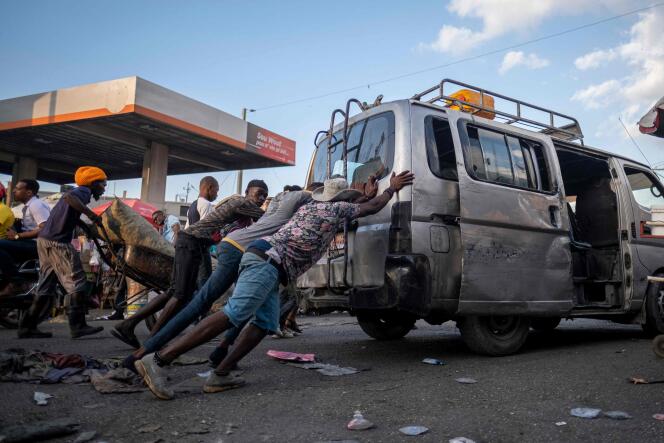 Des personnes poussent une camionnette de transport public Tap Tap, tombée en panne de carburant, devant une station-service fermée à Port-au-Prince, en Haïti, le 29 octobre 2021.