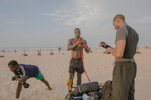 Alois Sambo et ses deux amis se préparent à commencer un entraînement sur la plage de Yoff, à Dakar, le 24 octobre 2021.