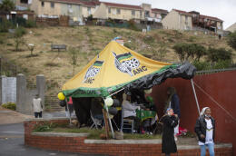 Supporters of the ruling African National Congress (ANC) man their party stand outside a polling station in Hangberg, an area of Houtbay, near Cape Town, on November 1, 2021, during South Africa's local elections. (Photo by RODGER BOSCH / AFP)