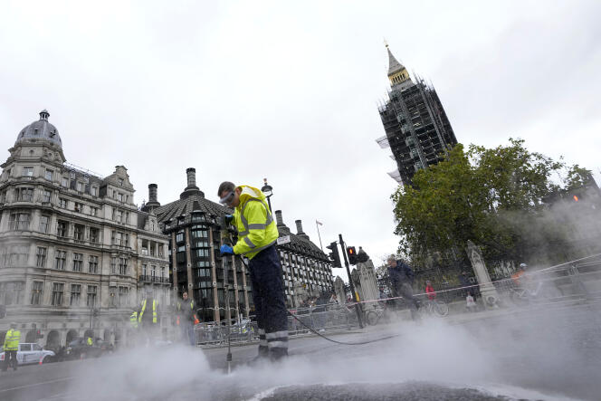 Un agent de nettoyage décolle la glu répandue sur la route devant le Parlement, après que les manifestants d’Insulate Britain se sont collés sur le macadam, à Londres, le 4 novembre 2021.
