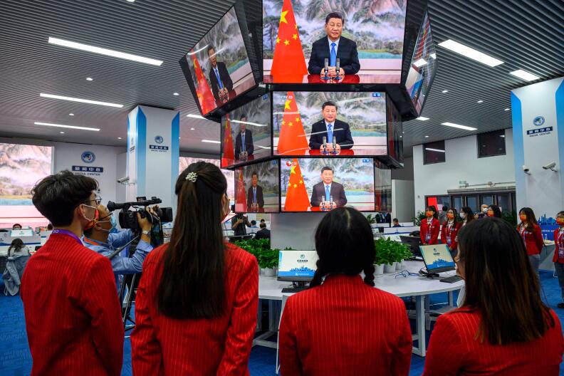 People watch screens showing live images of China's President Xi Jinping speaking during the opening ceremony of the China International Import Expo (CIIE), at the media center of the CIIE in Shanghai on November 4, 2021. China OUT (Photo by AFP)