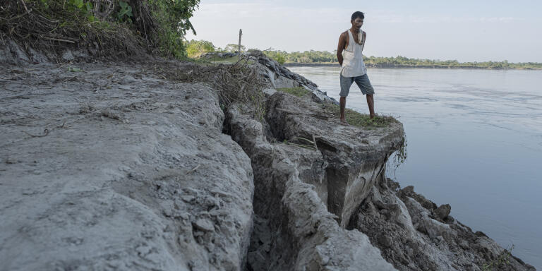 A villager in Salmara village in Majuli is standing on the broken bank of the river where the soil erosion is happening rapidly.