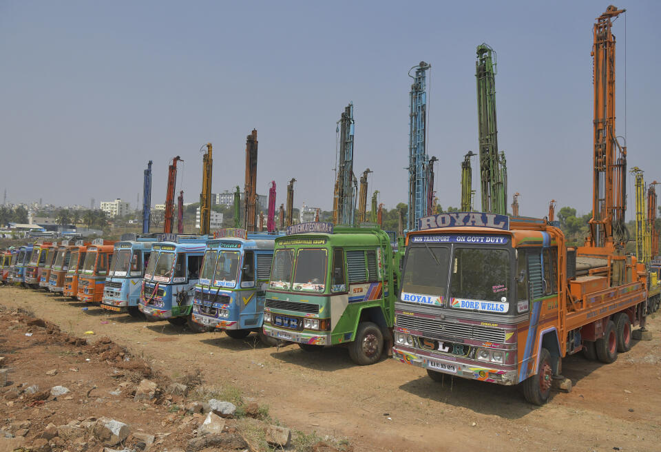 Trucks equiped with drilling rigs are seen parked at an open ground in Bangalore on February 16, 2021 as a mark of protest against the recent nationwide hike in fuel prices. (Photo by Manjunath Kiran / AFP)