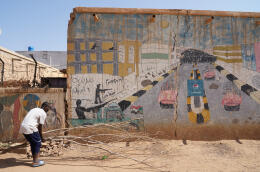 un jeune homme bouge de bois devant une fresque peinte sur un mur du quartier Al Abassiy , l'un des quartiers révolutionnaires les plus actifs d'à Omdrouman le 7 novmbre 2021.