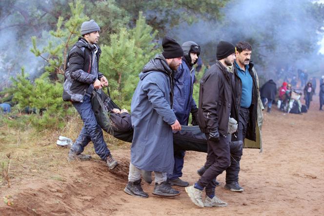 Des migrants originaires du Moyen-Orient portent leur ami malade à la frontière entre la Pologne et la Biélorussie, lundi 8 novembre 2021.