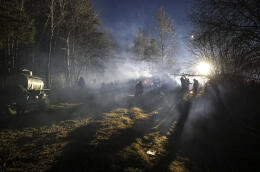 Migrants walk at a tent camp set by migrants from the Middle East and elsewhere gathering at the Belarus-Poland border near Grodno, Belarus, late Wednesday, Nov. 10, 2021. The European Union has accused Belarus' authoritarian President Alexander Lukashenko of encouraging illegal border crossings as a "hybrid attack" to retaliate against EU sanctions on his government for its crackdown on internal dissent after Lukashenko's disputed 2020 reelection. (Ramil Nasibulin/BelTA pool photo via AP)