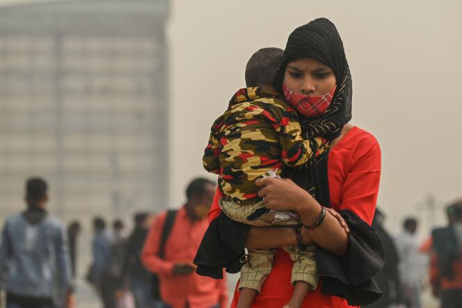 Une femme porte un enfant sur une passerelle de la capitale indienne, qui enregistre des niveaux de pollution atmosphérique très alarmants, le 12 novembre 2021.