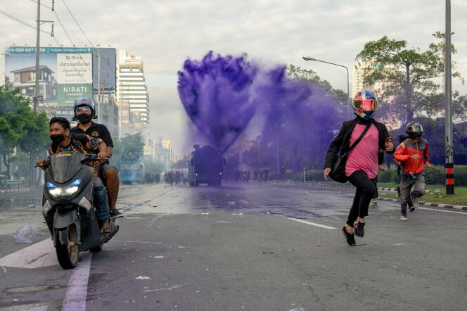 Protesters escape police water jets in Bangkok's Din Daeng neighborhood on August 29, 2021.