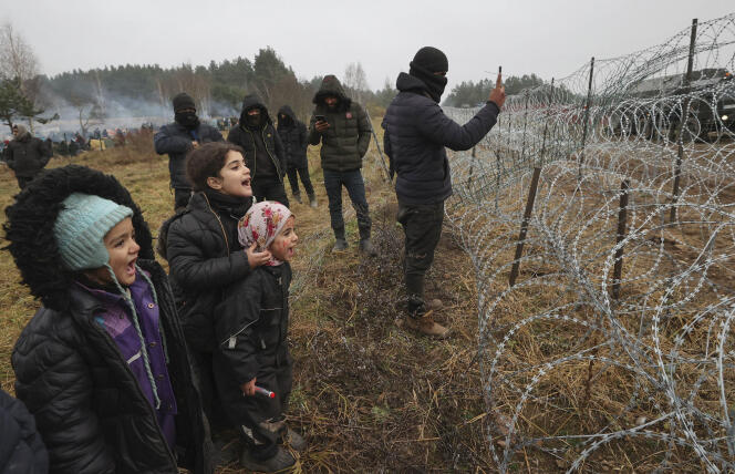 Des migrants font face à des barbelés à la frontière entre la Biélorussie et la Pologne, le 17 novembre 2021.