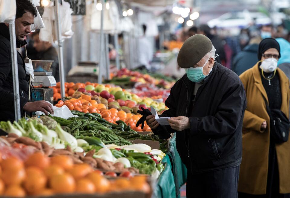 A man wearing a facemask for protective measures does his grocery shopping at the Barbes Market, on March 18, 2020, in Paris, as a strict lockdown came into in effect in France to stop the spread of COVID-19, caused by the novel coronavirus. - A strict lockdown requiring most people in France to remain at home came into effect at midday on March 17, 2020, prohibiting all but essential outings in a bid to curb the coronavirus spread. The government has said tens of thousands of police will be patrolling streets and issuing fines of 135 euros ($150) for people without a written declaration justifying their reasons for being out (Photo by JOEL SAGET / AFP)