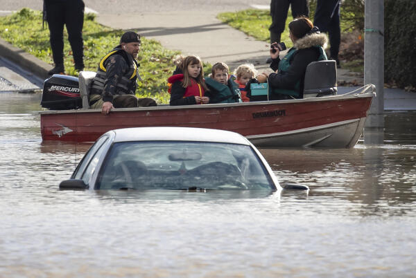 A woman and children stranded by flooding are rescued by boat by a volunteer in Abbotsford, British Columbia on November 16, 2021.