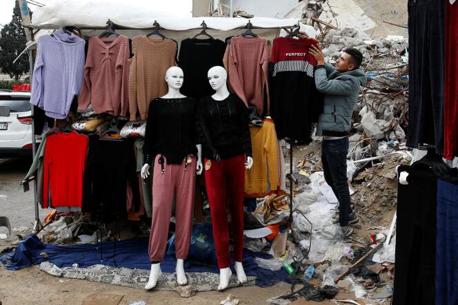 A clothing stand is set up in front of the rubble of a store destroyed by Israeli airstrikes in May, in Gaza, on November 20, 2021.