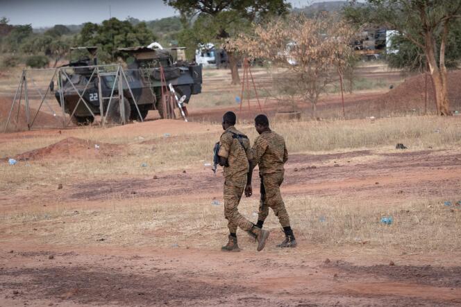 Des officiers burkinabés passent à proximité d’un des véhicules du convoi militaire français, à Kaya (Burkina Faso), le 20 novembre 2021.