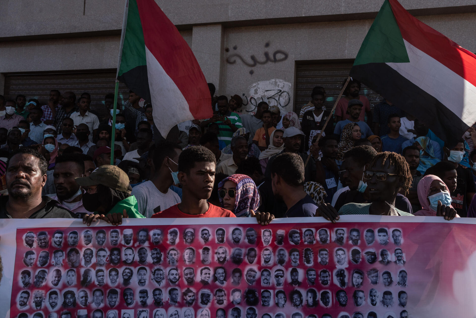Des Soudanais tiennent des drapeaux et des photos de martyrs pendant une manifestation à Bahri, dans la banlieue de Khartoum, le 17 novembre 2021.