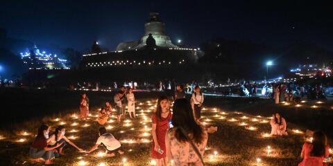 This photo taken on November 18, 2021 shows people taking part in the Tazaungdaing festival, also known as the Festival of Lights, at the pagoda in Mrauk U in Myanmar's Rakhine state. (Photo by AFP)