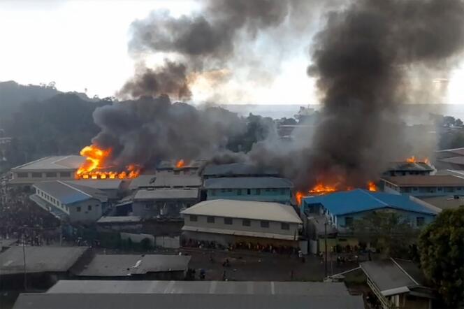 Capture d’écran montrant des bâtiments du quartier de Chinatown en feu, à Honiara, le 25 novembre 2021.