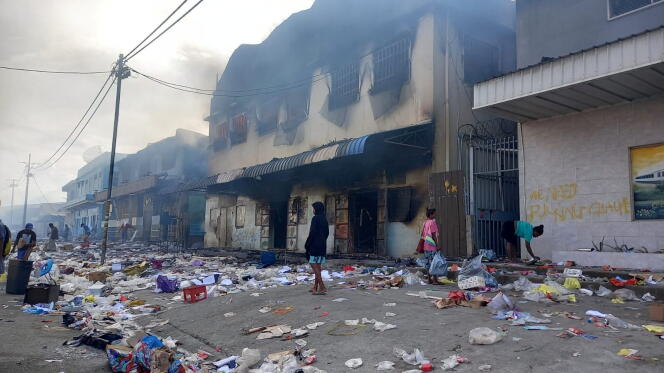Mensen tussen puin voor een brandend gebouw na dagen van onrust in Honiara, Salomonseilanden, 26 november 2021.
