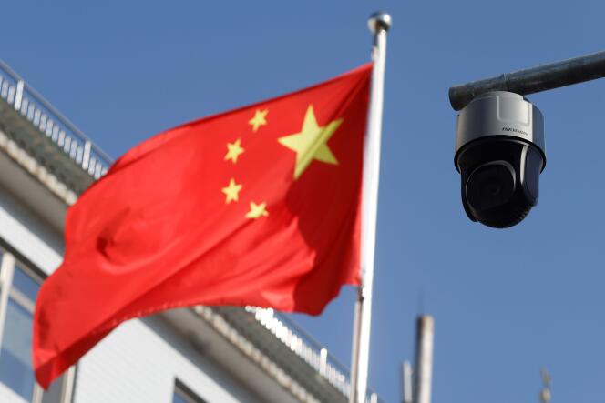 Une caméra de surveillance donnant sur une rue est photographiée à côté d’un drapeau chinois flottant à proximité, à Pékin, en Chine, le 25 novembre 2021.