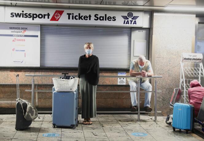 Des passagers attendent la confirmation de leur vol, devant le comptoir de Swissport, à l’aéroport de Johannesbourg, en Afrique du Sud, le 28 novembre 2021.