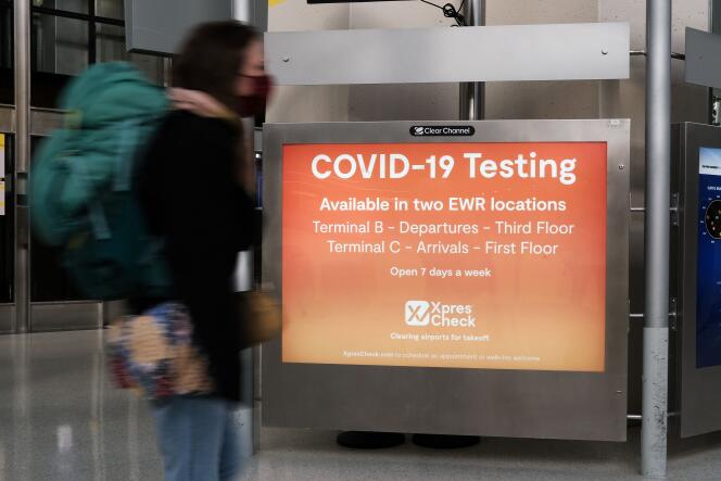 A medida que la variante Omicron se extiende por todo el mundo en el aeropuerto de Newark en Nueva Jersey el 30 de noviembre de 2021, un cartel insta a los viajeros a visitar Covit-19.