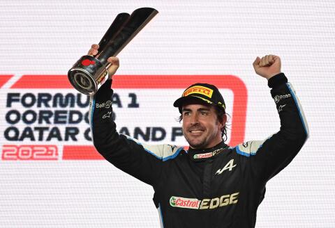 Alpine's Spanish driver Fernando Alonso raises his 3rd-place trophy on the podium following the Qatari Formula One Grand Prix at the Losail International Circuit, on the outskirts of the capital city of Doha, on November 21, 2021. (Photo by ANDREJ ISAKOVIC / AFP)