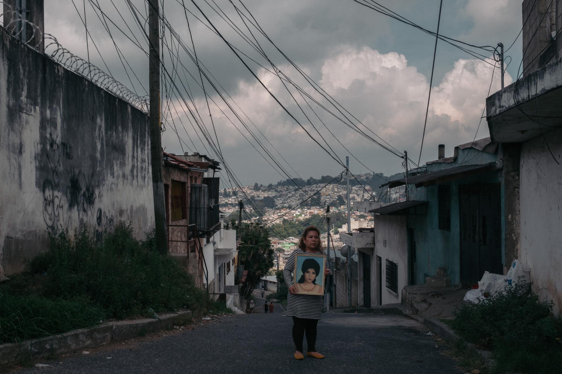 Andrea, la demi-sœur de Javier M., porte le portrait de leur mère décédée, Rosa, le 7 juin 2021, à Ciudad de Guatemala.