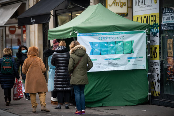 Des personnes patientent pour un test de dépistage devant une pharmacie rue du Four dans le 6e arrondissement de Paris, le 7 décembre 2021.
