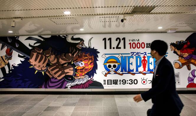Un homme passe devant une affiche avec les personnages de l’anime « One Piece » à la gare de Shibuya à Tokyo, le 18 novembre 2021, avant la sortie du millième épisode trois jours après.