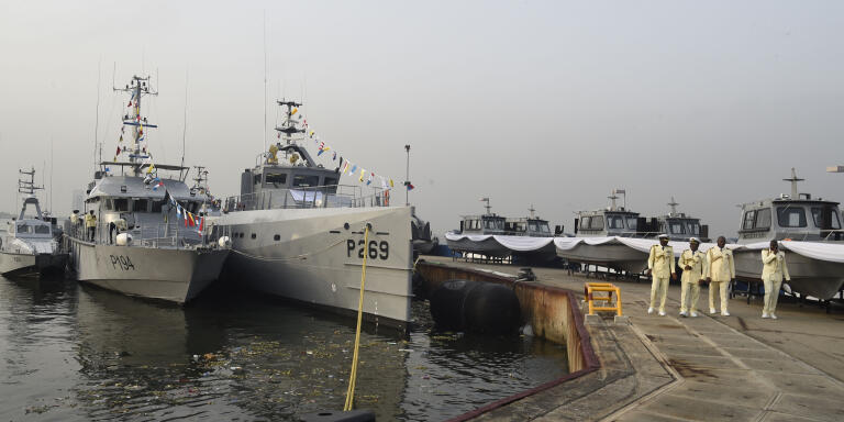 Nigerian Naval officers walk past recently acquired warships, boats and locally built Seaward Defence Boat inducted into naval fleet at the naval dockyard in Lagos, on December 9, 2021. Nigerian President Mohammadu Buhari has inaugurated and inducted to the naval fleet recently acquired warship and Seaward Defence Boat built locally by naval engineers to boost the Navy’s efforts in the fight against maritime crimes in the Gulf of Guinea region.  (Photo by PIUS UTOMI EKPEI / AFP)