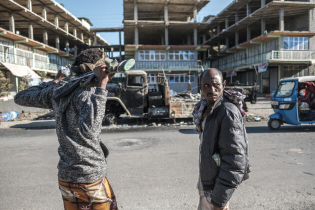 Des hommes de la milice Amhara se tiennent au bord d’une route devant un véhicule militaire qui aurait été détruit par une attaque de drone, à Shewa Robit (Ethiopie), le 8 décembre 2021.