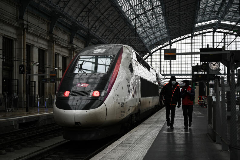 SNCF personnel members walk past a TGV (high speed train) at the railway station in Bordeaux, southwestern France on November 25, 2021 on the day the metropolis of Bordeaux is expected to vote on a participation of 354 million euros to finance the extension of the Paris-Bordeaux LGV (high-speed rail line). - The LGV project tears the majority between the socialists and the ecologists, led by the mayor of Bordeaux who prefers an improvement of "daily trains". (Photo by Philippe LOPEZ / AFP)