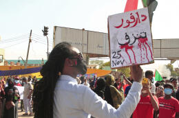 A demonstrator holds a sign reading in Arabic "Darfur is bleeding" during a protest demanding civilian rule in the Sudanese capital's twin city of Omdurman on December 13, 2021. (Photo by AFP)