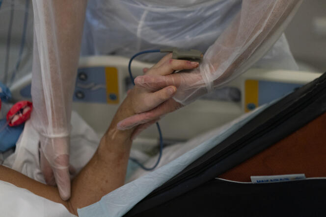 Une infirmière tient la main d’un patient atteint du Covid-19 sous ventilateur, à l’hôpital de la Timone, à Marseille, le 31 décembre 2021.