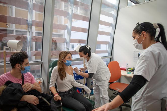 Au centre de vaccination de l’hôpital de la Timone, à Marseille, le 30 décembre 2021, Julie Sampo (22 ans) redoute la vaccination au moment de se faire piquer. Avec Rayan Cherfeddine (à gauche), ils vont recevoir leur première dose du vaccin de Pfizer pour pouvoir voyager en février.