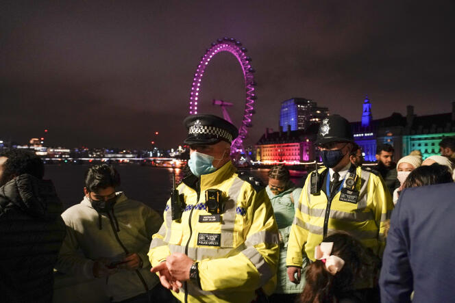 Police officers wearing face masks patrol Westminster Bridge as people gather to celebrate New Years in London on December 31, 2021.