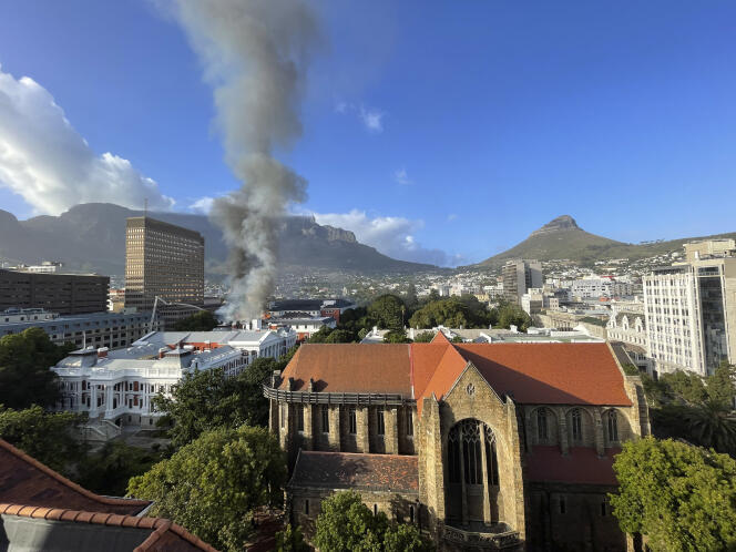 A plume of smoke rises above the Houses of Parliament behind St. George's Cathedral in Cape Town, South Africa, Sunday January 2, 2022.