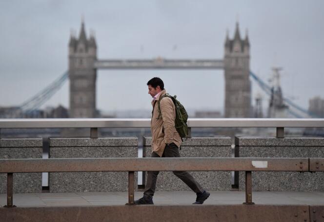Un homme traverse le London Bridge, avec le Tower Bridge derrière, pendant l’heure de pointe matinale, alors que le gouvernement britannique recommande le télétravail, dans le quartier financier de la City de Londres, le 4 janvier 2022.