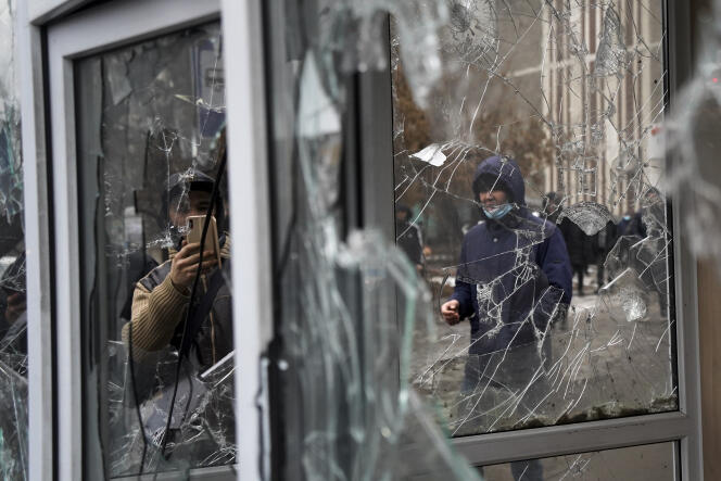 A protester against the sharp rise in fuel prices, especially LPG, photographs the windows of a police kiosk smashed by protesters in Almaty, Kazakhstan on January 5, 2022.