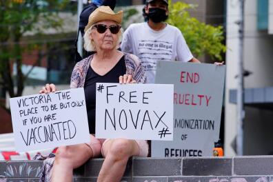 A protestor holds signs outside Park Hotel, where Serbian tennis player Novak Djokovic is believed to be living, in Melbourne, January 6, 2022. REUTERS/Sandra Sanders