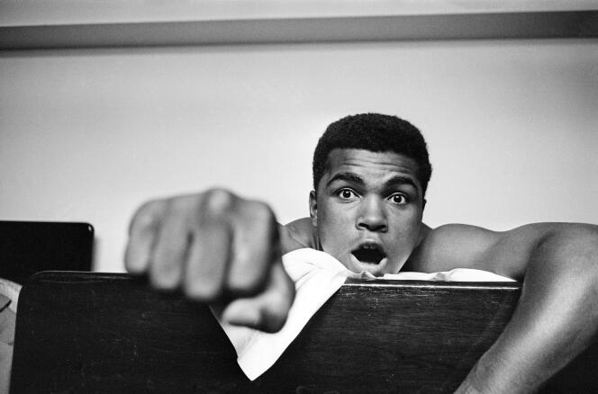 27 mai 1963 : le boxeur américain poids lourd Cassius Clay (futur Muhammad Ali) est allongé sur son lit d’hôtel à Londres. Il lève cinq doigts pour prédire le nombre de rounds qu’il lui faudra pour mettre K.O. le boxeur britannique Henry Cooper.