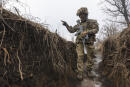 A Ukrainian soldier walks in a trench at the line of separation from pro-Russian rebels, Donetsk region, Ukraine, Monday, Jan. 10, 2022. President Joe Biden has warned Russia's Vladimir Putin that the U.S. could impose new sanctions against Russia if it takes further military action against Ukraine. (AP Photo/Andriy Dubchak)